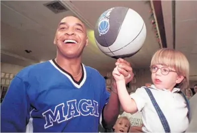  ?? EILEEN MARIE GARCIA ?? Former Harlem Globetrott­ers star Curly Neal helped bring the NBA to Orlando and served as a Magic community ambassador. He showed cancer patient Codey Fears, 2, how to spin a basketball during a fundraiser to help the Fears family pay for medical expenses.