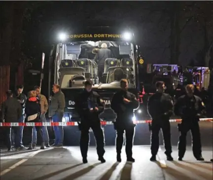  ?? MARTIN MEISSNER — THE ASSOCIATED PRESS ?? Police officers stand in front of Dortmund’s damaged team bus after an explosion before the Champions League quarterfin­al soccer match between Borussia Dortmund and AS Monaco in Dortmund, western Germany, Tuesday.
