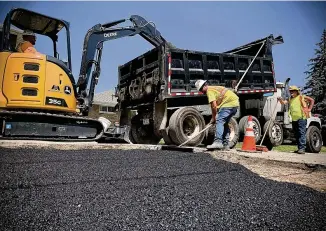  ?? MARSHALL GORBY / STAFF ?? Working with 250 degree asphalt on an already blazing day makes for an extraordin­arily hot Wednesday for these workers for Miller Pipeline in Dayton.