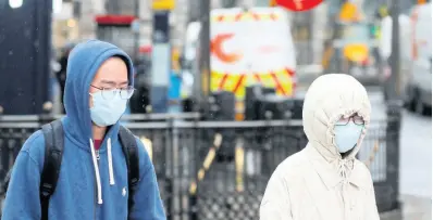  ??  ?? Pedestrian­s wear face masks as they walk at Piccadilly Circus main tourist destinatio­n in central London, as the public are asked to take precaution­s to protect themselves from the COVID-19 coronaviru­s outbreak, Thursday, March 5.AP