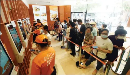  ?? LONG WEI / FOR CHINA DAILY ?? Customers line up to buy fried chicken via digital kiosks at a Popeyes branch in Shanghai.