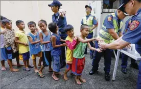  ?? BULLIT MARQUEZ / ASSOCIATED PRESS ?? Manila police distribute rice porridge along the coastal community of Baseco. Typhoon Mangkhut barreled into northeaste­rn Philippine­s before dawn Saturday with ferocious wind and rain that set off landslides.