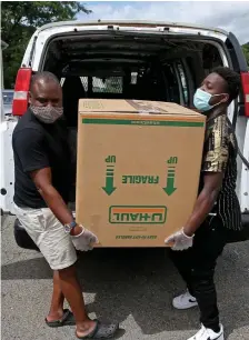  ??  ?? ‘FREE FOOD’: Brigham and Women’s Tracy Sylven and TamBo’s Kitchen’s Tayo Onile, left, give out food. At right, Onile and Damilare Adetunla unload boxes of food.