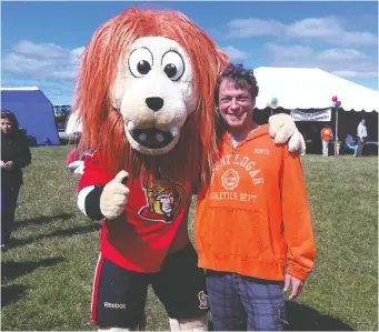  ?? COURTESY OF GINA PARKHOUSE ?? Ottawa Senators logo and mascot creator Kevin Caradonna shares a moment with Spartacat. The graphic designer, an integral part of the NHL team's history, died of liver disease on Monday.