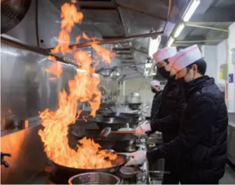  ??  ?? Chefs work in the kitchen of a restaurant in Changsha, Hunan Province, central China, on February 12