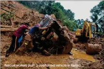  ?? Rescue workers push a overturned vehicle in Kerala ??