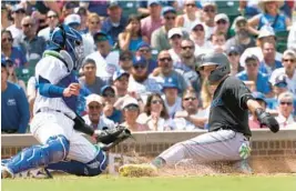  ?? CHARLES REX ARBOGAST/AP ?? Cubs catcher P.J. Higgins tags out the Marlins’ Miguel Rojas at home in the third inning Saturday in Chicago.