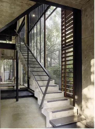  ??  ?? OPEN SPACES
This staircase makes a bold statment indoors (left); the living cum dining room opens into the kitchen, complete with a breakfast counter (below); the living room has floor to ceiling glass windows (right)