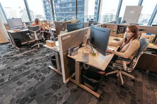  ?? Photos by William Luther / Staff photograph­er ?? Jessica Faur, right, connects to her laptop Wednesday at the offices on the 10th floor of the Frost Bank tower. Colleague Brenda Trevino works in the background.