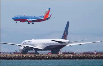  ?? JANE TYSKA — BAY AREA NEWS GROUP ?? A Southwest Airlines plane lands in the area of runways 28 left and 28 right as a United Airlines plane waits on a taxiway at San Francisco Internatio­nal Airport as seen from Bayfront Park in Millbrae on July 20, 2017.