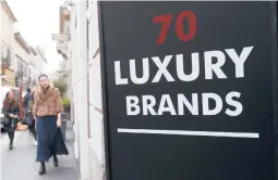  ?? ANTONIO CALANNI/AP ?? A woman walks past a shop in 2016 in Milan, Italy. U.S. shoppers outspent the Chinese in pursuit of the latest fashion trends, according to a new study.