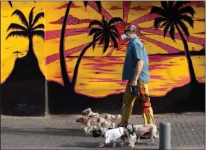  ?? (AP/Oded Balilty) ?? A man wears a face mask Monday as he walks several dogs in Tel Aviv, Israel.