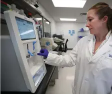  ??  ?? FINDING THE ANSWERS: Liz Bionelli, wearing a borrowed lab coat, works on a pathogen detection system at LexaGene.