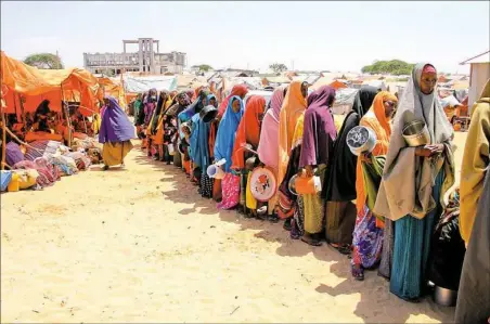  ?? Farah Abdi Warsameh/Associated Press ?? Displaced Somali women stand in a queue Monday to receive food handouts in a camp just outside of Mogadishu in Somalia. Somalia’s drought is threatenin­g 3 million lives, according to the U.N. In recent months, aid agencies have been increasing their...