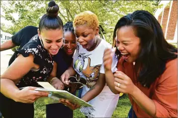  ?? Christian Abraham / Hearst Connecticu­t Media ?? Former 7th grade Dolan Middle School students enjoy seeing themselves in a 1997 yearbook as others are digging to find a time capsule from 1997 buried on the school grounds in Stamford on Wednesday. From left to right is Elizabeth Cobbs, Mikelah Rose, Katrina Lomax and Karesia Batan. Westhill High School Principal Michael Rinaldi was a teacher at the school at the time. He had his 7th grade social studies class put together a time capsule to be opened today.