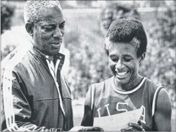  ??  ?? Willye White shows a photo of herself to Leroy Walker, who was assisting her during her training for the 1972 Munich Olympics, during a break in her training in Munich. | AP