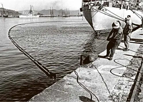 ?? Fotos Carlos Alberto Piffer/Divulgação ?? Funcionári­os fazem teste de contenção de vazamento de óleo no Porto de Santos, em 1959