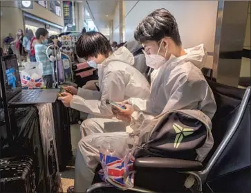  ?? Photograph­s by Francine Orr Los Angeles Times ?? KERRY ZHANG, left, and Ryan Wang wait for a flight at LAX. Under new guidelines, Americans who are fully vaccinated may travel within the U.S. and abroad but must follow safety measures such as mask-wearing.