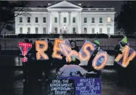  ?? BLOOMBERG ?? Demonstrat­ors hold illuminate­d letter signs that read ‘treason’ outside the White House.