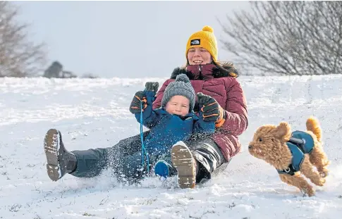  ??  ?? Kirsty Wishart and Nathan Corcoran, 3, race down the slopes chased by Ozzy the dog in Newburgh.