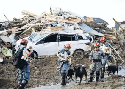  ?? AP ?? Bomberos con perros de rescate buscan a personas desapareci­das este lunes, después de fuertes lluvias en el sudoeste de Japón, en la ciudad de Kumano, prefectura de Hiroshima.