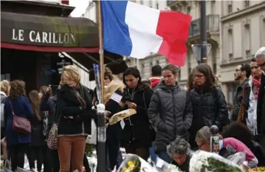  ?? BENOIT TESSIER/REUTERS ?? Mourners pay tribute to the victims of the Paris attacks outside Le Petit Cambodge and Le Carillon restaurant­s on Tuesday.