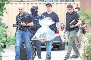  ?? — Gambar Reuters ?? POLIS dilihat di luar salah sebuah rumah yang disasar dalam serbuan antikegana­san merentasi pinggir bandar utara-barat di Melbourne, Australia semalam.