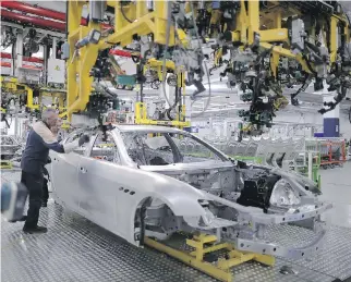  ?? MARCO BERTORELLO/AFP/GETTY IMAGES FILES ?? Employees work on the assembly line of the Maserati brand at a factory in Grugliasco near Turin, Italy. About 2,000 workers at the plant will be put on extended furloughs.