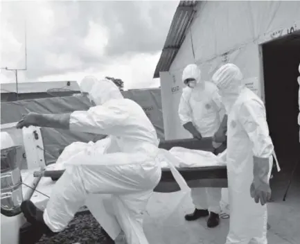  ??  ?? Health workers in protective gear remove the body of a man they suspect died from the Ebola virus at an American treatment center Friday in Liberia. WHOwill miss a target dateMonday in the battle to control the virus. Abbas Dulleh, The Associated Press