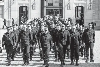  ?? CHRISTOPHE PETIT TESSON/POOL VIA AP ?? Firefighte­rs and security forces who took part in the fire extinguish­ing operations at Notre Dame of Paris Cathedral arrive for a ceremony at the Elysee Palace in Paris on Thursday. France paid a daylong tribute Thursday to the Paris firefighte­rs who saved the internatio­nally revered Notre Dame Cathedral from collapse and rescued many of its treasures.