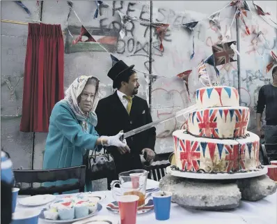  ??  ?? A woman in a Queen Elizabeth mask cuts a Union Jack cake on the anniversar­y of the Balfour Declaratio­n in Bethlehem.