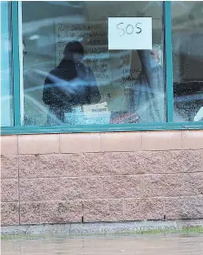  ??  ?? An employee at the Magna plant on Patillo Road jokingly holds up an SOS sign during heavy rain and flooding in the Tecumseh area Thursday.