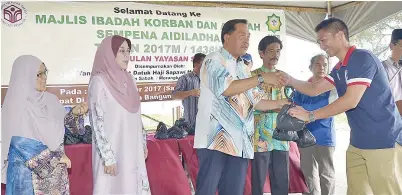  ??  ?? diperhatik­an oleh Rosmawati dan Dr. Karim mengagihka­n daging korban di majlis itu.