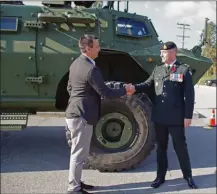  ?? BARB AGUIAR/Special to The Daily Courier ?? Westbank First Nation Coun. Thomas Konek, left, shakes hands with Maj. Kevin Mead of the Canadian Armed Forces after unveiling the Syilx translatio­n of the name of the B.C. Dragoons’ new armoured vehicle.