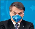  ??  ?? Jair Bolsonaro, in a mask, declares if he had the virus, it would be little more than a cold