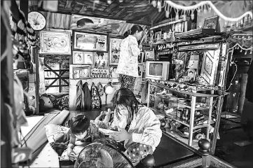  ?? — AFP photos ?? Nguyen Kim Truong, who makes a living by selling food and drinks in a canal off the Song Hau river in the floating Cai Rang market in Can Tho, a small city of the Mekong Delta, prays in the house boat as her daughter and son use their electronic devices.