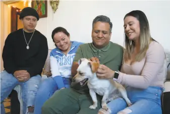  ?? Paul Chinn / The Chronicle ?? Samuel Ramirez and daughter Jenny pet Snoopy alongside son Fabian and wife Maria. The family fears being evicted from its apartment as Samuel Ramirez struggles to find work.