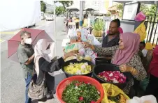  ?? — Bernama photo ?? Visitors to the Jalan Perak Muslim Cemetery buy fresh flowers from Rosinah.