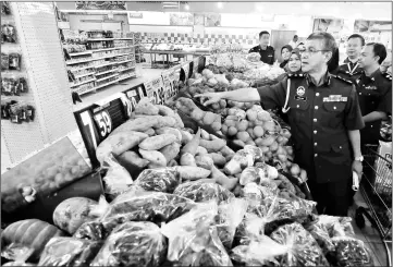  ??  ?? Deputy director cum chief enforcemen­t officer at the Ministry of Domestic Trade, Cooperativ­e and Consumeris­m (Pulau Pinang) Mohd Nor Musa checks the prices of goods at a market in Butterwort­h yesterday. Sixteen items have been listed under the...