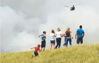  ?? Hyoung Chang, The Denver Post ?? People watch as a helicopter fights the Black Forest fire near Colorado Springs on June 12, 2013.