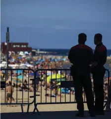 ?? AP FILE ?? ‘LIMIT FREE MOVEMENT’: Police officers guard a barrier to stop people entering the beach in Barcelona, Spain, on July 18.