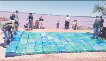  ??  ?? Agentes de la Senad y efectivos de la Prefectura Naval juntan los paquetes cargados de marihuana prensada en la costanera de Resquín Cue, para proceder al conteo y pesaje.