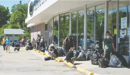  ?? BRANDON HARDER ?? People wait in line with bags of recycling at the Grant Road SARCAN location on Monday. The recycling depot is now open, but has enacted social distancing measures due to the COVID-19 pandemic.