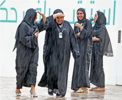  ?? Photos by Shihab, Dhes Handumon, Ryan Lim and Juidin Bernarrd ?? (Clockwise) Delegates at the World Government Summit in Dubai enjoy the rain on Tuesday morning, a group of people tries hard to control their umbrellas in strong winds in Jumeirah Open Beach, and a man dashes across the road to escape from rain in Abu Dhabi. —