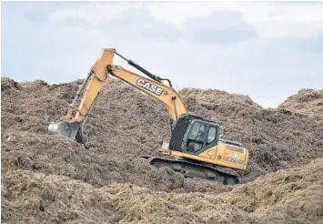  ?? MICHAEL LAUGHLIN/STAFF PHOTOGRAPH­ER ?? A heavy equipment operator moves large mounds of wood mulch at Fort Lauderdale’s Holiday Park on Tuesday. The mulch was made from trees damaged by Hurricane Irma.