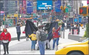  ??  ?? Visitors to New York’s Time Square pose for a photo with a street performer working for tips dressed as Batman.