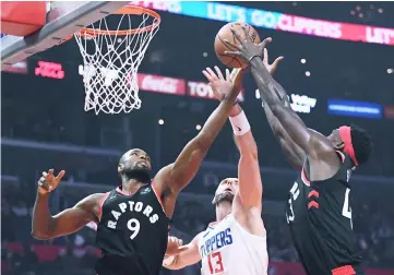  ??  ?? Marcin Gortat (centre) of the LA Clippers junps for a rebound between Serge Ibaka (left) and Pascal Siakam of the Toronto Raptors during the first half at Staples Centre in Los Angeles, California. — AFP photo