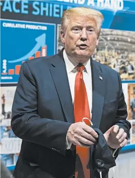  ?? ALEX BRANDON/AP ?? President Donald Trump holds a face mask May 21 at a Ford plant in Ypsilanti, Michigan. Amid the pandemic, Trump has declined to don a mask while staging large gatherings.