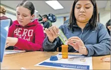  ?? [CHRIS LANDSBERGE­R/ THE OKLAHOMAN] ?? Students Margaret Mendz and Jennifer Hinojosa, from left, follow the directions to the drug disposal worksheet during the launch of an interactiv­e prescripti­on drug safety course designed for high school students at Capitol Hill High School in Oklahoma City on Friday.