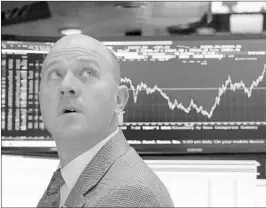  ?? RICHARD DREW/AP ?? Specialist Jay Woods works the New York Stock Exchange floor as the chart behind him shows the day’s volatility.